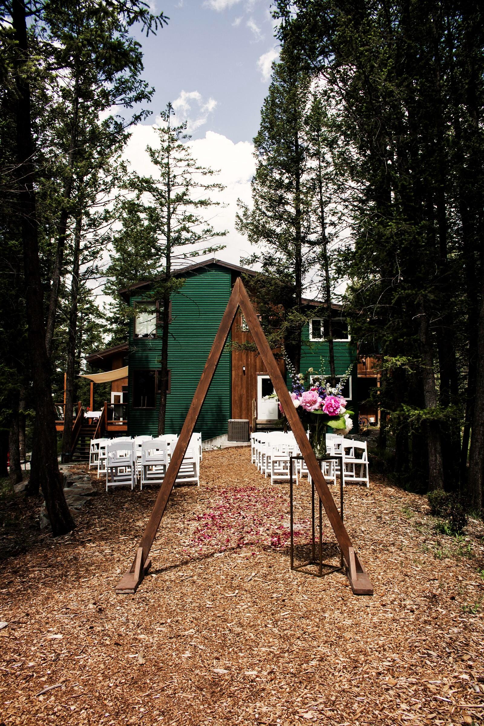 Ceremony arch and white chairs set in front of the lodge