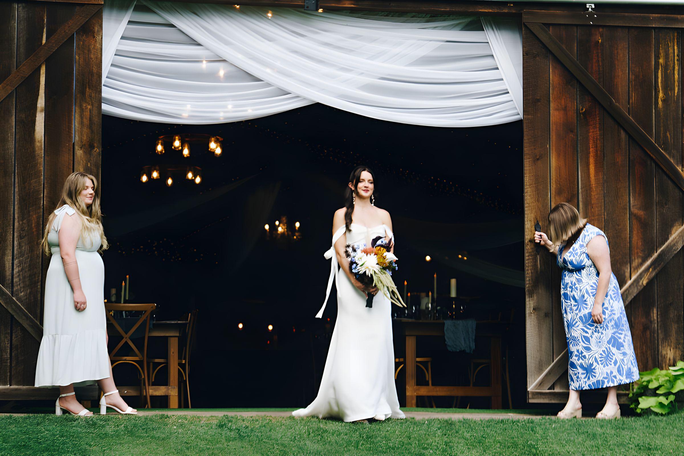 Bride with her bouquet in the draped barn doorway before the reception