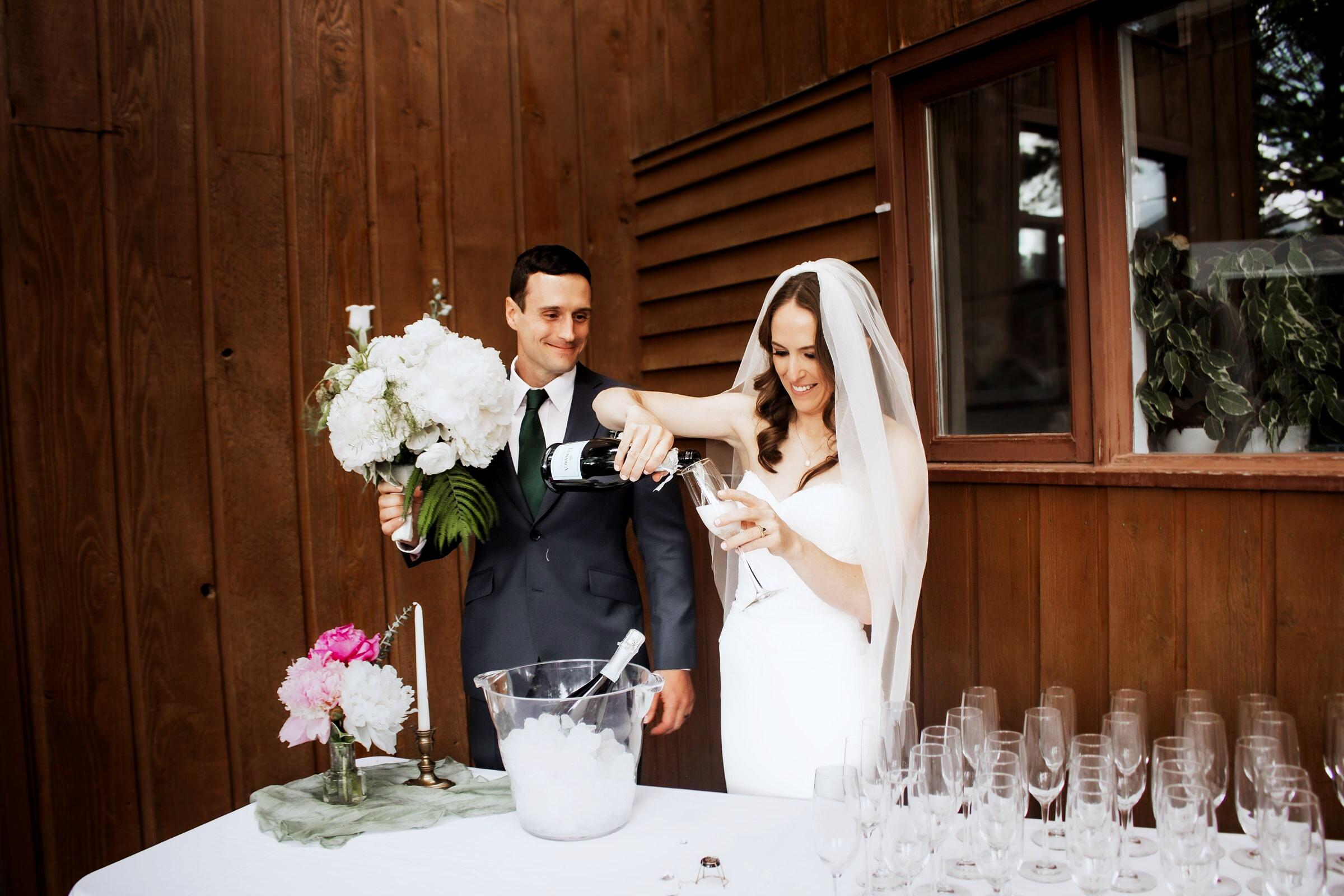 Newlyweds pouring champagne beside the bridal bouquet at a mountain lodge