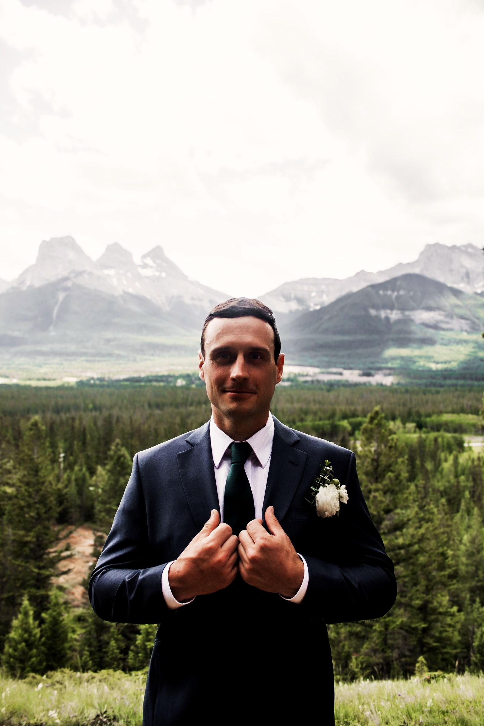 Groom with a white boutonniere in front of the Three Sisters