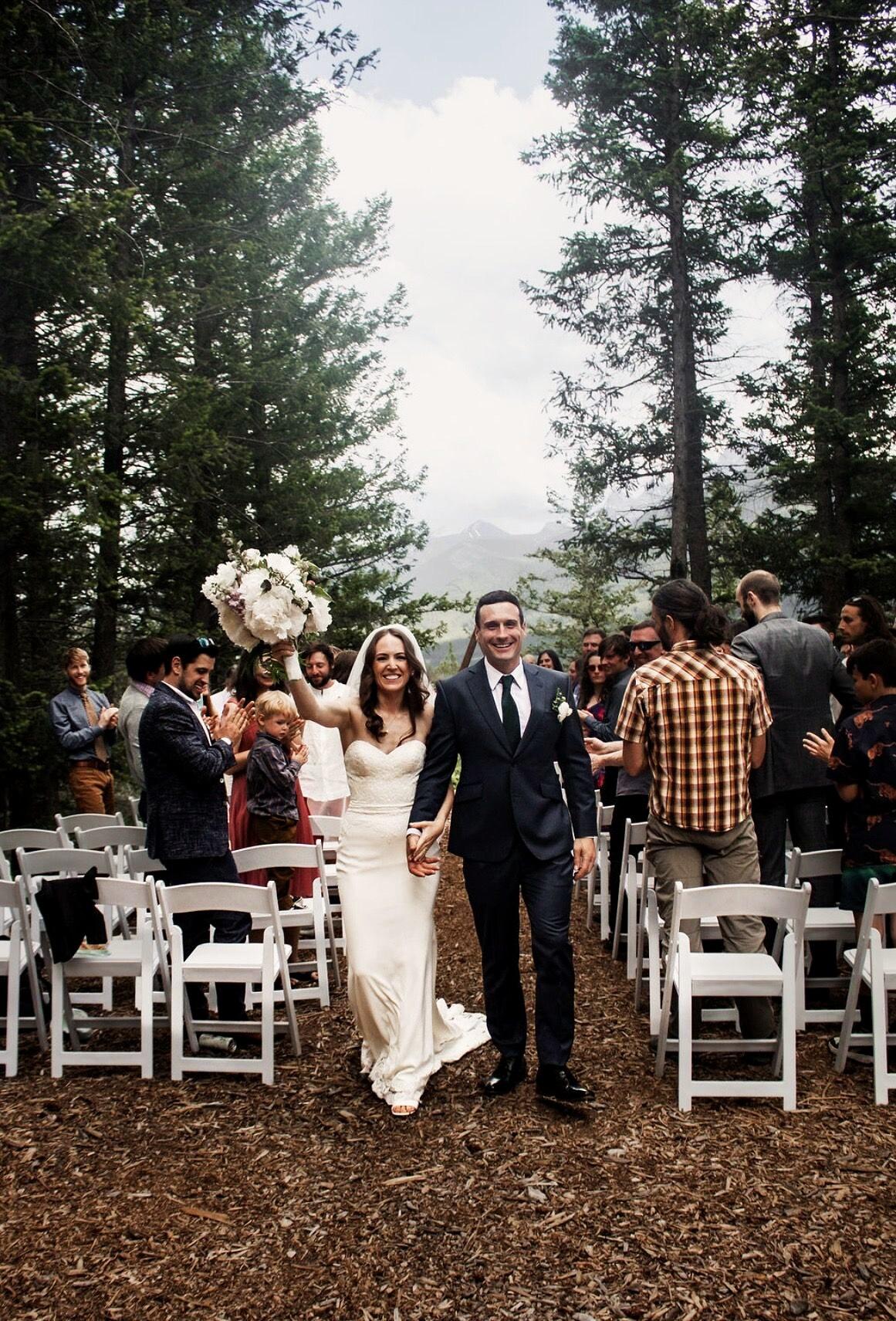 Newlyweds walking back down the aisle, bouquet raised