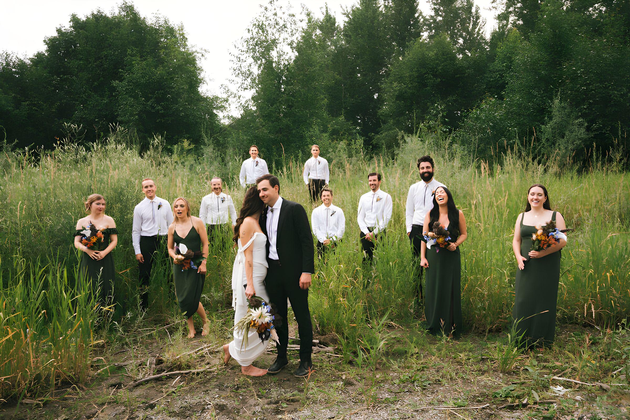 The whole wedding party standing in a tall-grass meadow