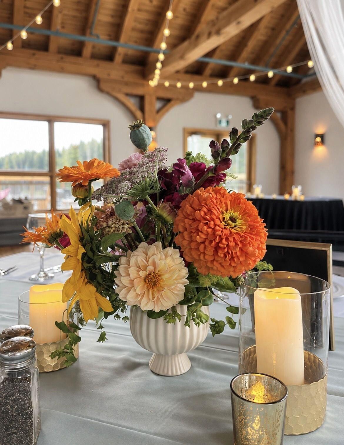 Orange dahlia centerpiece with candles on a reception table